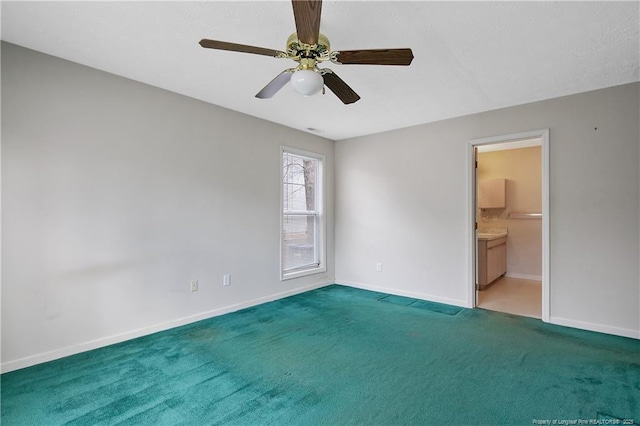 carpeted spare room featuring a ceiling fan and baseboards