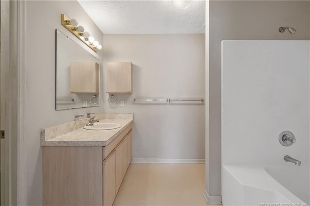 full bath featuring a textured ceiling, shower / washtub combination, vanity, and baseboards