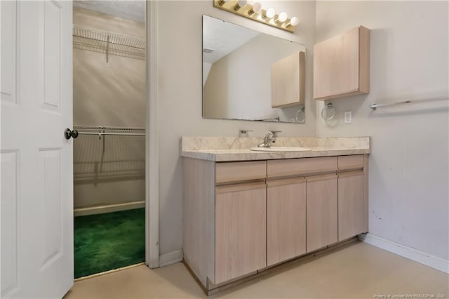 bathroom featuring a walk in closet, vanity, and baseboards