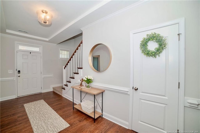 entryway with stairs, visible vents, a raised ceiling, and wood finished floors