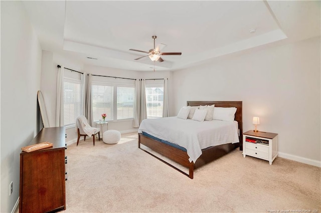 bedroom with carpet floors, a tray ceiling, and baseboards