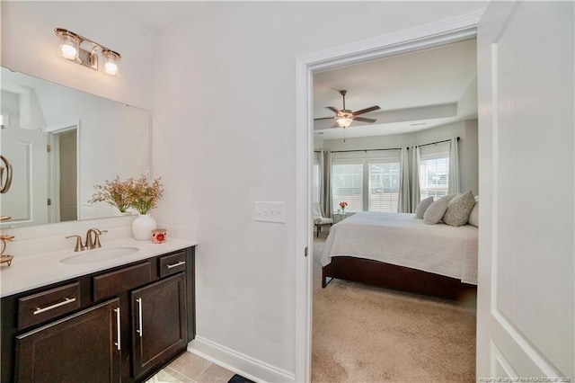 interior space featuring ceiling fan, ensuite bathroom, vanity, and baseboards