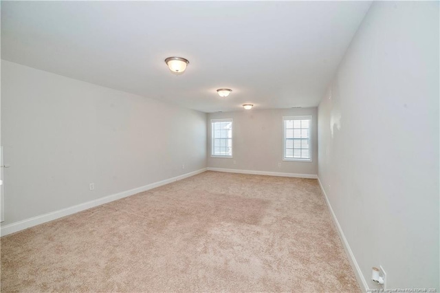 unfurnished room with light carpet and baseboards