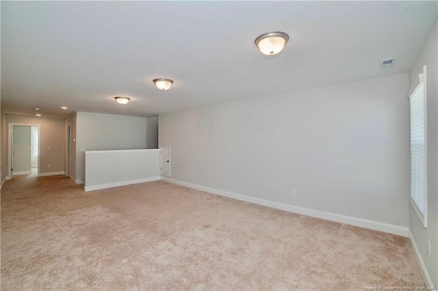 spare room with baseboards, visible vents, and light colored carpet