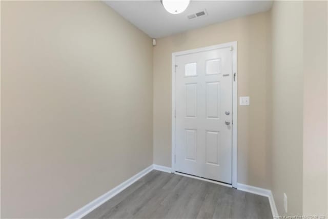 doorway to outside featuring visible vents, baseboards, and wood finished floors