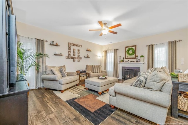 living area with a fireplace, a ceiling fan, and wood finished floors