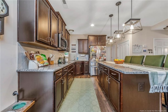 kitchen featuring stainless steel appliances, a kitchen island, backsplash, and light stone countertops