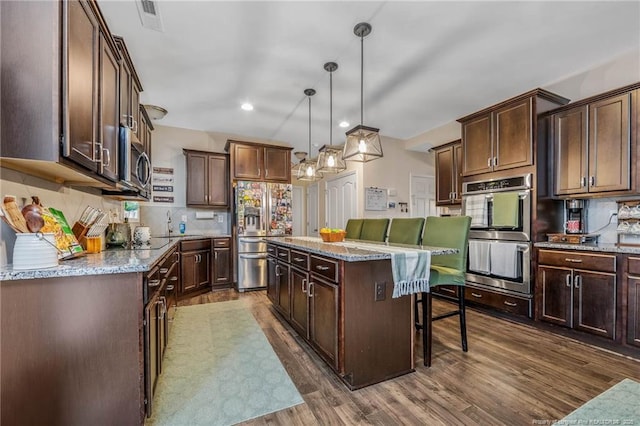 kitchen featuring appliances with stainless steel finishes, a center island, a kitchen breakfast bar, and decorative backsplash