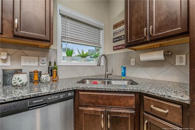 kitchen with stone countertops, backsplash, dark brown cabinets, stainless steel dishwasher, and a sink