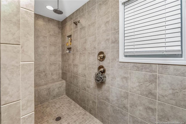 full bath featuring tiled shower and a healthy amount of sunlight