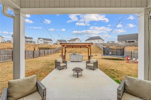 view of patio with a fire pit, a trampoline, a fenced backyard, and a residential view