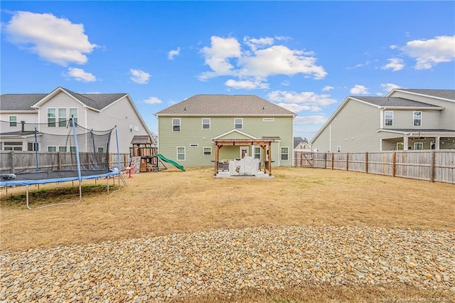 rear view of property with a trampoline, a playground, a yard, a patio area, and a fenced backyard