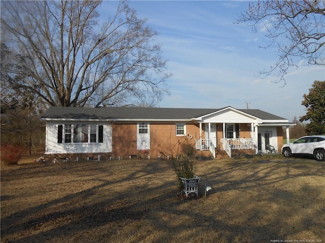 view of front facade featuring brick siding, a porch, and a front yard