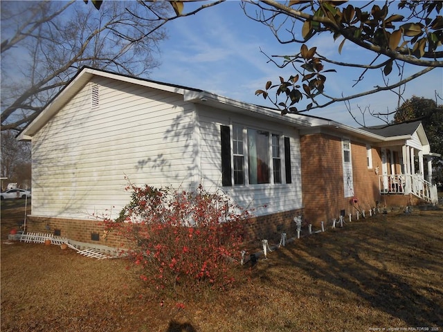 view of property exterior with crawl space, brick siding, and a yard