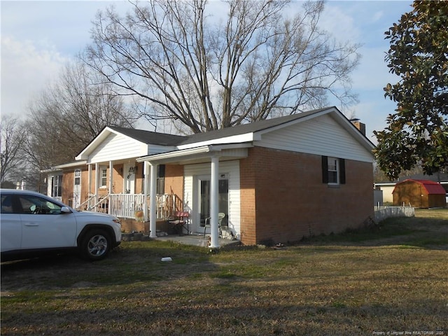 view of property exterior featuring a porch, a lawn, and brick siding