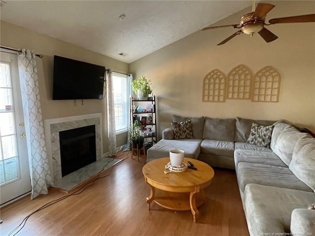 living room featuring lofted ceiling, wood finished floors, a high end fireplace, and a healthy amount of sunlight