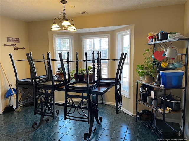 dining area featuring a textured ceiling, dark tile patterned flooring, visible vents, and baseboards