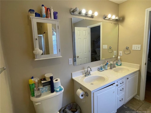 bathroom featuring double vanity, a sink, toilet, and tile patterned floors