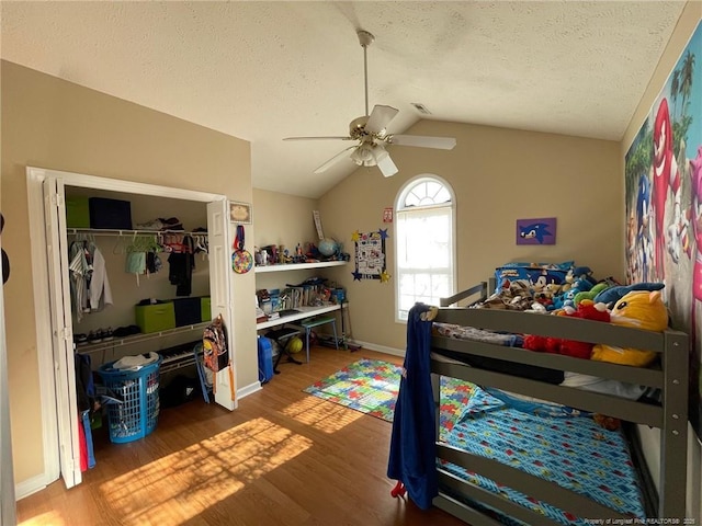 bedroom featuring lofted ceiling, a closet, a textured ceiling, and wood finished floors