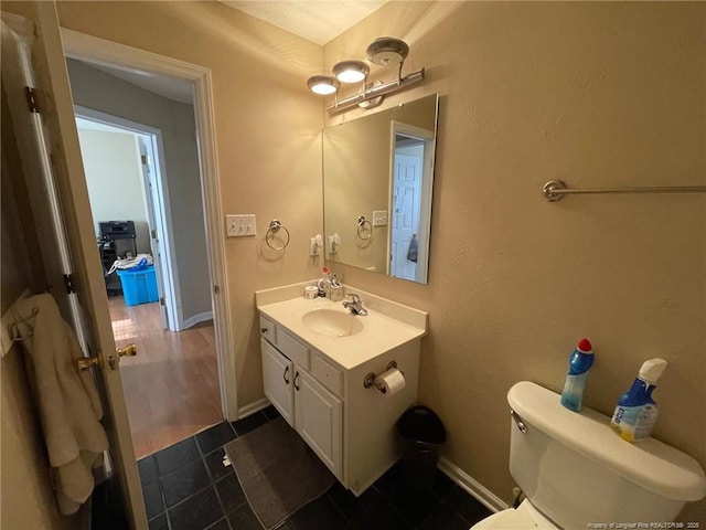 half bath with tile patterned floors, vanity, toilet, and baseboards