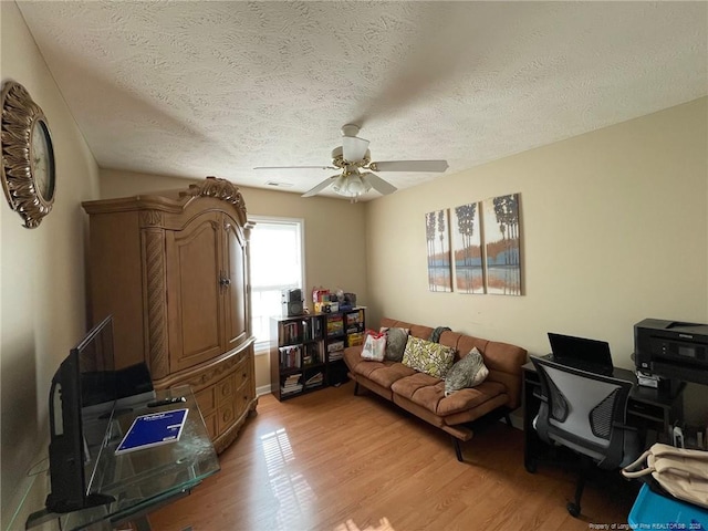 interior space featuring light wood-style floors, a textured ceiling, and a ceiling fan