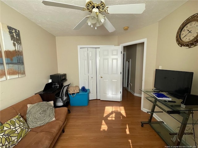 office area featuring a textured ceiling, ceiling fan, wood finished floors, and baseboards