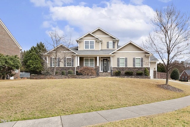 craftsman-style house featuring stone siding, driveway, a front yard, and fence