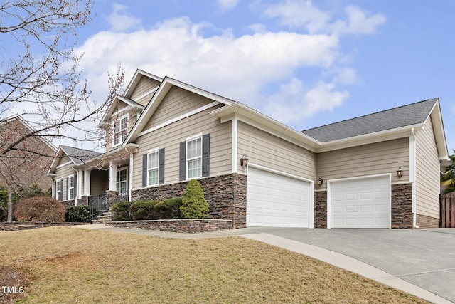 craftsman house with stone siding, driveway, a front yard, and a garage