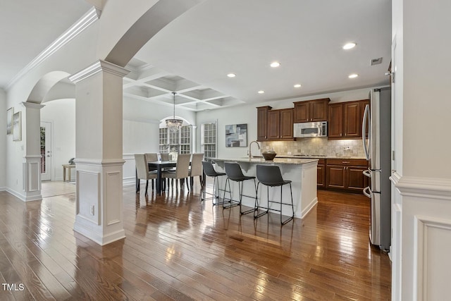 kitchen featuring backsplash, dark wood-type flooring, decorative columns, coffered ceiling, and stainless steel appliances