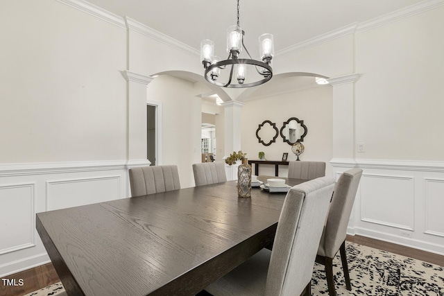 dining space featuring decorative columns, arched walkways, dark wood-type flooring, and crown molding