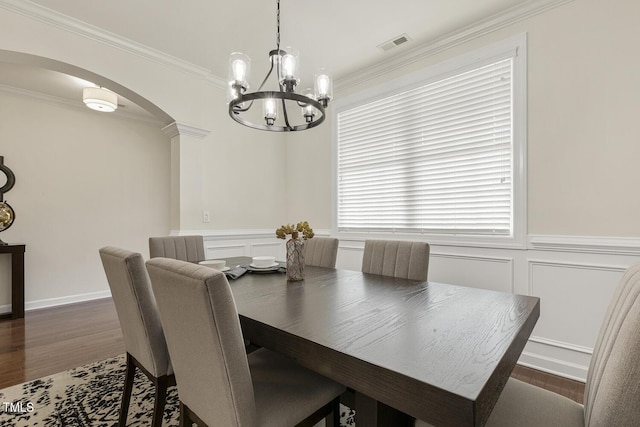 dining space with visible vents, ornamental molding, wood finished floors, arched walkways, and wainscoting