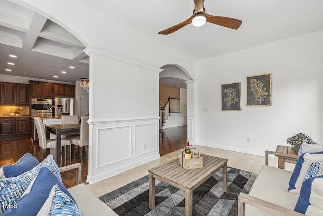 tiled living room featuring stairway, beamed ceiling, recessed lighting, arched walkways, and coffered ceiling