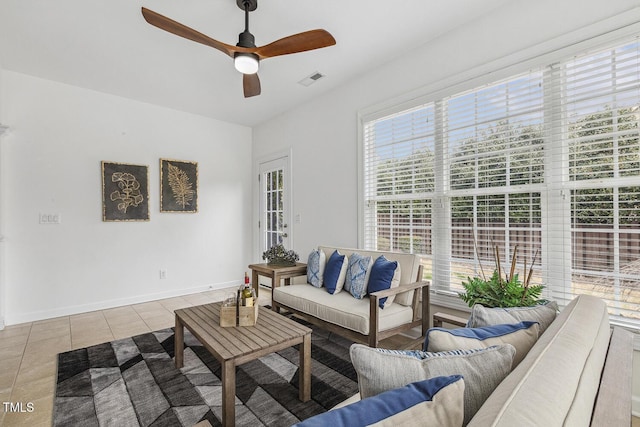 living area featuring tile patterned flooring, visible vents, baseboards, and a ceiling fan