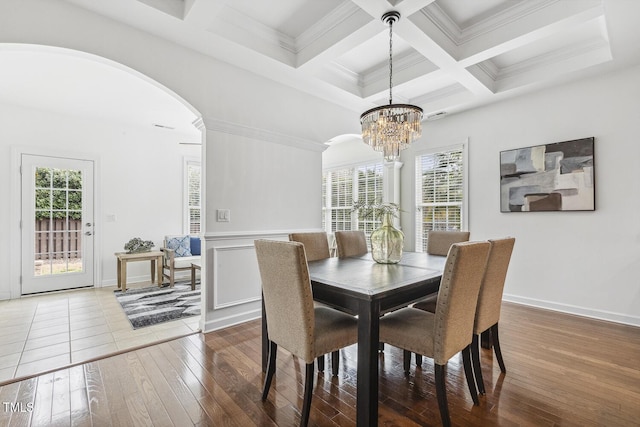 dining area with beam ceiling, coffered ceiling, arched walkways, and hardwood / wood-style flooring