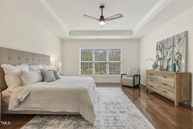 bedroom featuring crown molding, a raised ceiling, baseboards, and wood finished floors