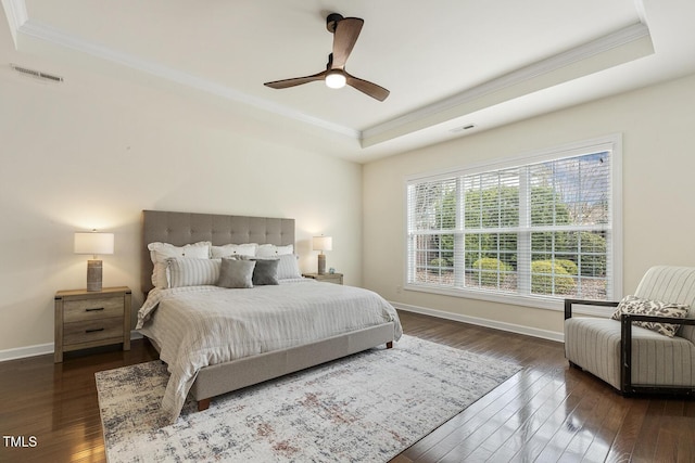 bedroom with a tray ceiling, hardwood / wood-style flooring, crown molding, and visible vents