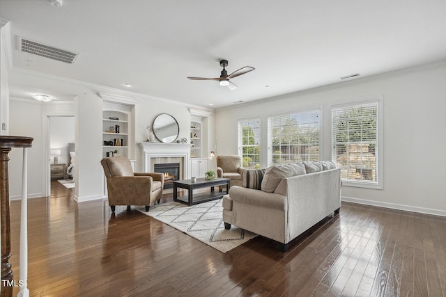 living area with visible vents, built in shelves, hardwood / wood-style floors, and crown molding