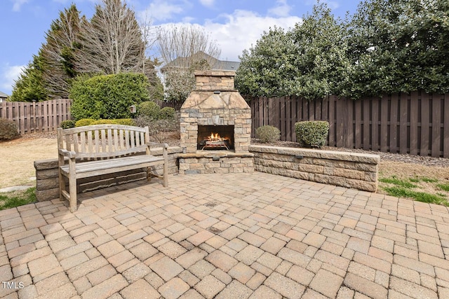 view of patio / terrace featuring an outdoor stone fireplace and a fenced backyard