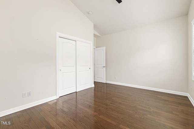 unfurnished bedroom featuring a closet, baseboards, high vaulted ceiling, and dark wood-style floors