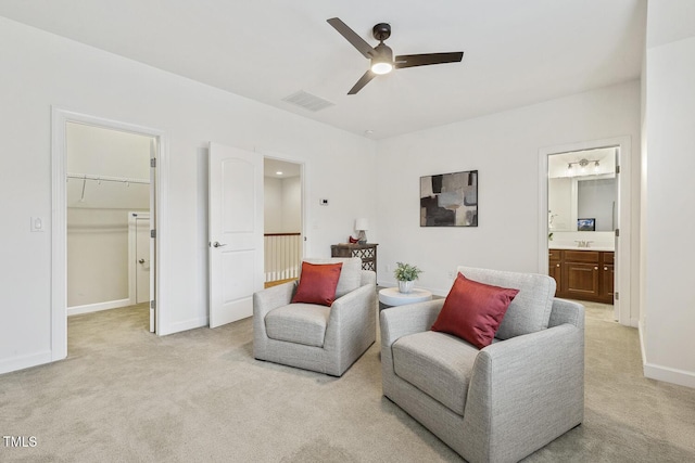 living area with visible vents, light colored carpet, a ceiling fan, and baseboards