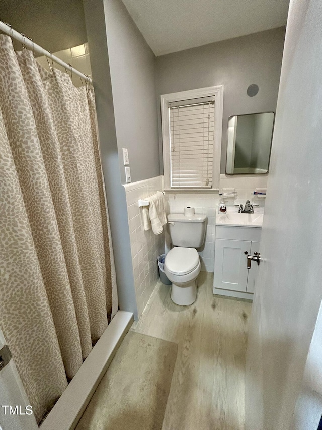 bathroom with tile walls, toilet, wainscoting, vanity, and wood finished floors