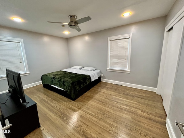 bedroom with ceiling fan, a closet, baseboards, and wood finished floors