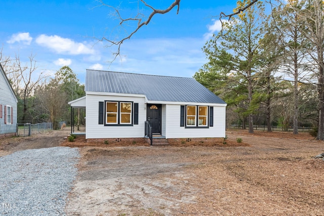 view of front of house with driveway, fence, and metal roof