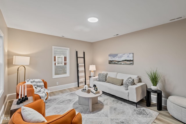 living area with baseboards, visible vents, and light wood-style floors