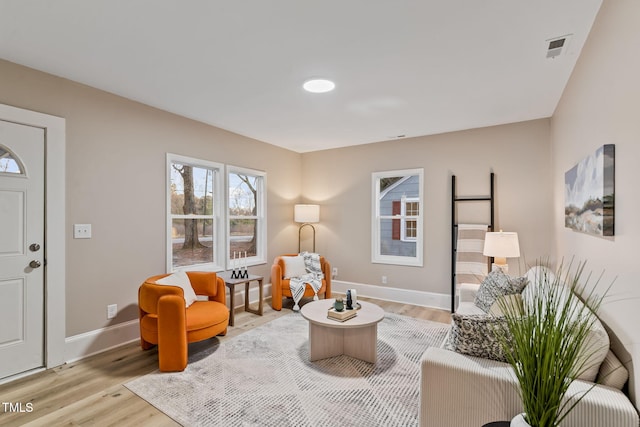 living area with visible vents, light wood-style flooring, and baseboards