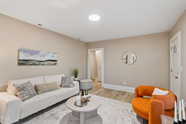 living area with light wood-style floors, visible vents, and baseboards