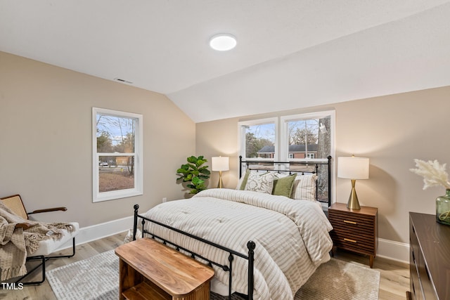 bedroom with lofted ceiling, light wood-style flooring, multiple windows, and visible vents