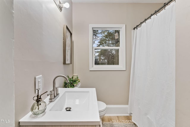 bathroom featuring baseboards, toilet, a shower with curtain, wood finished floors, and vanity