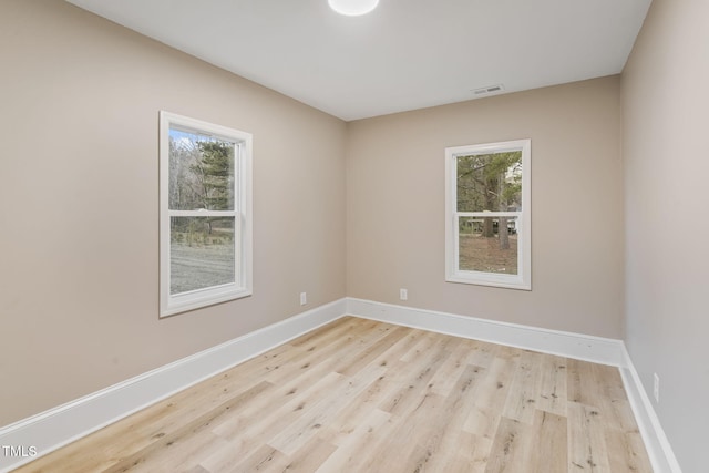 empty room featuring light wood-style floors, visible vents, and baseboards