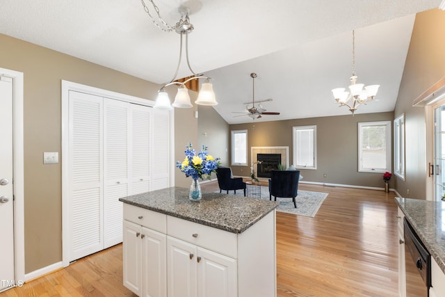 kitchen featuring decorative light fixtures, a kitchen island, light wood-type flooring, dishwasher, and a tile fireplace